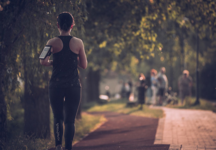 Eine Freizeitsportlerin beim Joggen im Park mit In Ear Kopfhörern